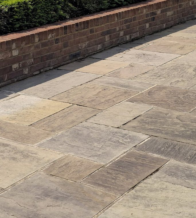 Clean sandstone patio slabs in full sun, the joints clear and the colour even